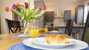 Ein Esstisch mit einem Croissant, einem Glas Orangensaft und einer Vase mit Tulpen.