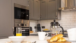Eine moderne Küche mit Edelstahlgeräten, einer Kaffeemaschine und Frühstücksartikeln auf der Arbeitsfläche.