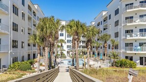 A multi-story hotel with balconies, a central pool, and palm trees. - Palm Beach C22  1 bd 1.5 bth coastal inspired condo great view updated remodeled (Orange Beach)