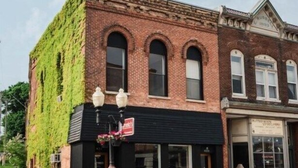 A two-story brick building with a black awning and a fire hydrant in front. - Historic Downtown Manistee Apartment (Manistee)