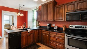 A kitchen with wooden cabinets, a dishwasher, a stove, and a coffee maker. - Historic Downtown Manistee Apartment (Manistee)