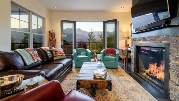 Un salon chaleureux avec une cheminée, un canapé en cuir et une vue sur les montagnes.
