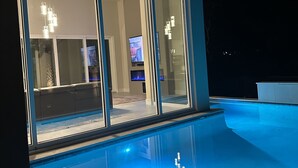 A modern house with a swimming pool, large glass doors, and a visible living room with a TV. - Luxury, privacy and serenity close to beach, private pool (Santa Rosa Beach)