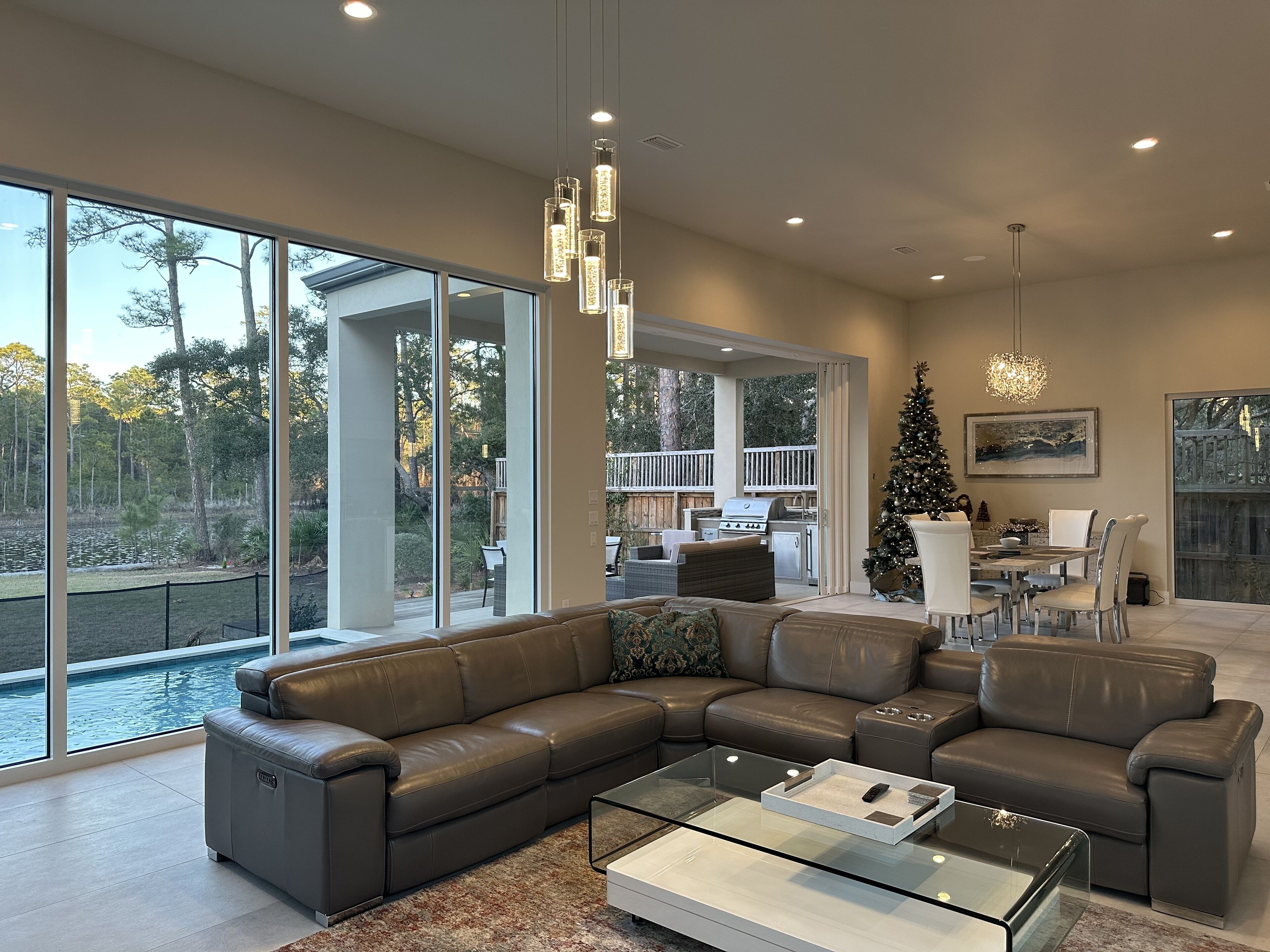 A spacious living room with a large sectional sofa, a glass coffee table, and a dining area with a Christmas tree.