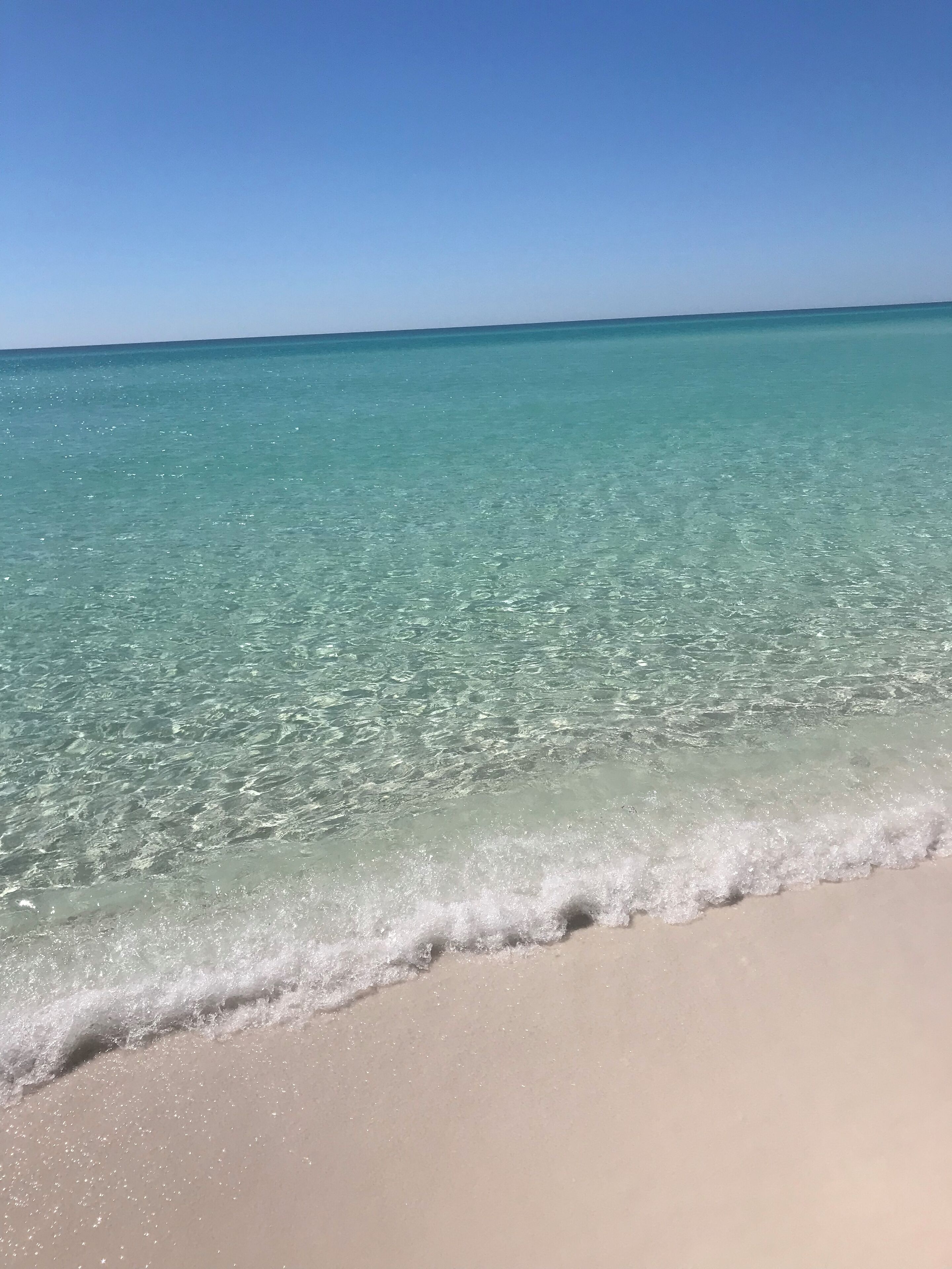 A beach with clear turquoise water and a sandy shore.