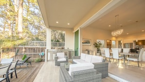 A spacious outdoor patio with modern furniture, a dining area, and a kitchen visible through an open door. - Luxury, privacy and serenity close to beach, private pool (Santa Rosa Beach)