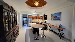 Une cuisine moderne dotée d’un îlot central, de meubles en bois et d’un luminaire au plafond en forme d’étoile.