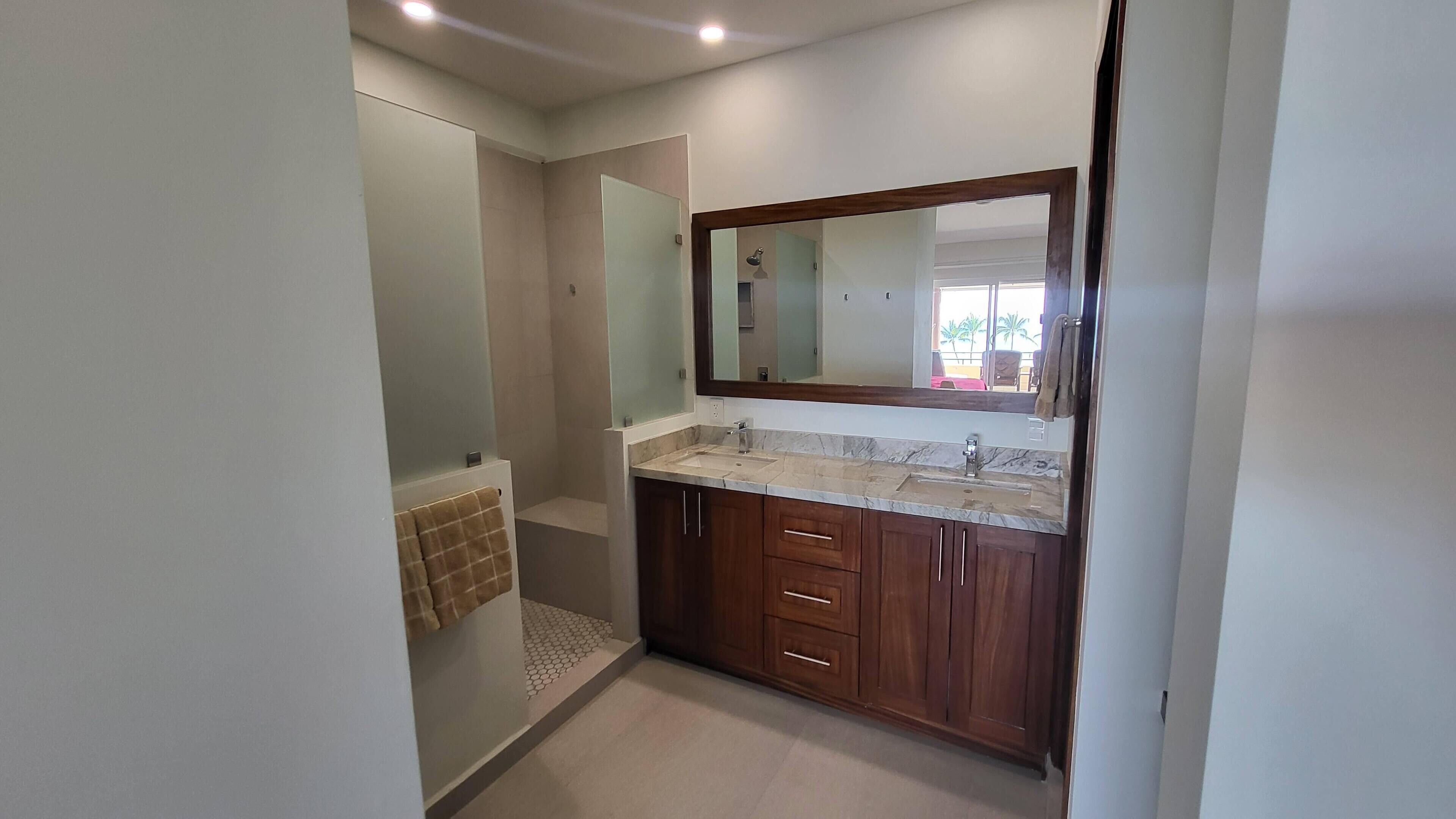 A modern bathroom with a large mirror, a sink, and wooden cabinets.