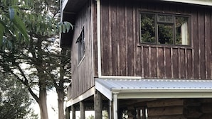 A rustic wooden house with a covered porch and a stone foundation. - Large, genuine, Log House. 857 Church Rd. Kaitaia (Kaitaia)