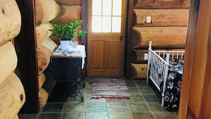 A log cabin interior with a wooden door, a small table with a plant, and a tiled floor. - Large, genuine, Log House. 857 Church Rd. Kaitaia (Kaitaia)