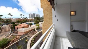 A balcony with a view of a resort area, including a pool and palm trees.