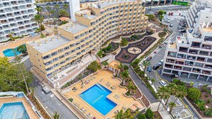 A hotel with multiple floors, a central courtyard with a swimming pool, and surrounding greenery.