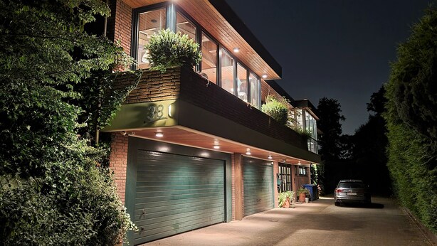 A modern two-story house with a garage, surrounded by greenery.