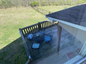 Una terrazza coperta all'aperto con tavolo e sedie, circondata da una recinzione in legno.