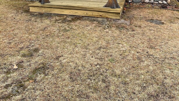 A rustic cabin with a stone foundation, wooden siding, and a porch with wooden posts. - Sage Lake Huron Cottage  (East Tawas)