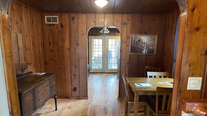 A wooden interior with a dining area, a wooden dresser, and a door leading outside. - Sage Lake Huron Cottage  (East Tawas)