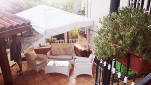 A patio area with outdoor furniture, including a sofa and chairs, a table, and a white umbrella providing shade. - House (Agropoli)