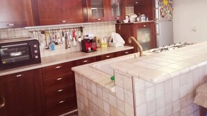 A kitchen with wooden cabinets, a microwave, a coffee maker, and a sink. - House (Agropoli)