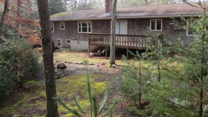 A two-story house with a wooden deck and a chimney. - Private 4 BR Ranch Tucked In The Woods 1.5 Miles From Beach (Falmouth)