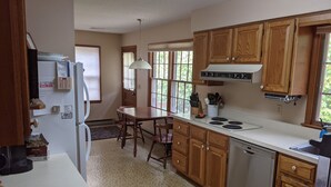 A kitchen with wooden cabinets, a white countertop, a stove, and a refrigerator. - Private 4 BR Ranch Tucked In The Woods 1.5 Miles From Beach (Falmouth)