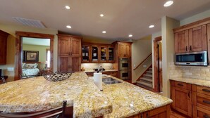 A kitchen with granite countertops, wooden cabinets, a stainless steel sink, and a microwave. - Cozy Family Escape with Access to Exclusive Golf (Sunriver)