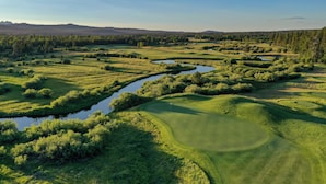 A golf course with water hazards, lush greenery, and distant mountains. - Cozy Family Escape with Access to Exclusive Golf (Sunriver)