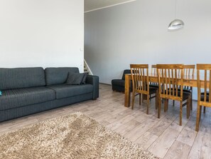 A modern living room with a grey sofa, wooden dining table with chairs, a fluffy rug, and a pendant light. - Skivillas 61 ukkohalla (b10) by Interhome (Hyrynsalmi)