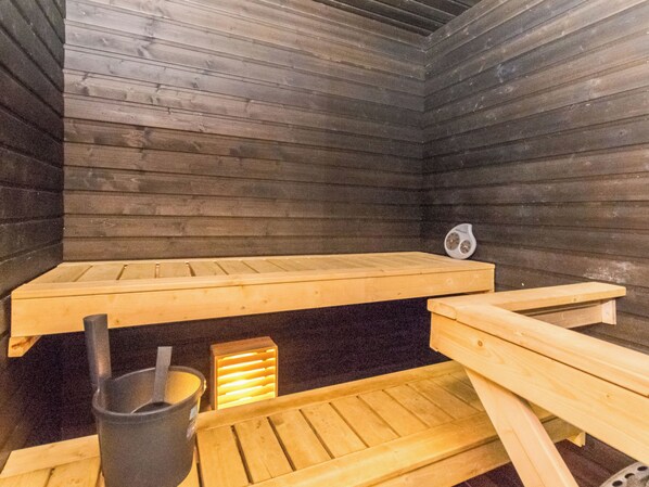 A sauna room with wooden benches and a heater.