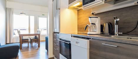 Een moderne keuken met een ingebouwde magnetron, koffiezetapparaat en vaatwasser.