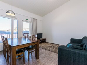 Una habitación con una mesa de madera, sillas, un televisor y un sofá.