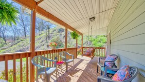 Eine überdachte Veranda mit Holzbalkonen, zwei Tische mit Stühlen und einem hängenden Blumentopf.
