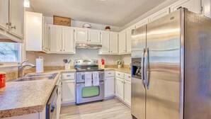 Eine moderne Küche mit weißen Schränken, Edelstahlgeräten, Granit Arbeitsplatten und einem Einbauofen.
