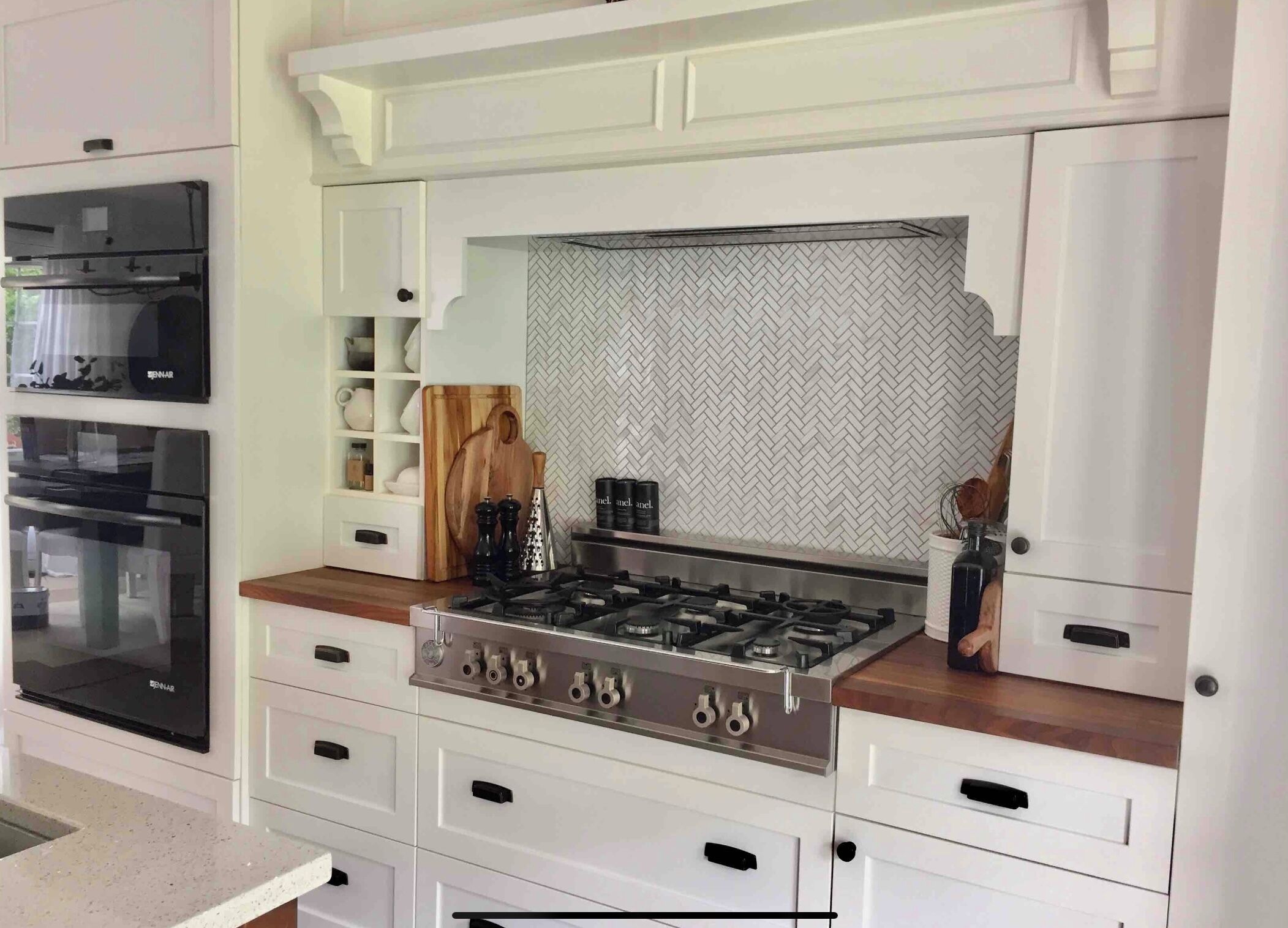 A modern kitchen with built-in appliances, including a gas stove, ovens, and a microwave.