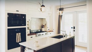 A modern kitchen with white cabinetry, a central island, a stove, and a sink.