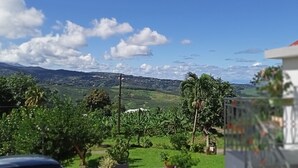 A view of a lush green landscape with a clear blue sky and scattered clouds. - Studio Paradis Caché Sainte-Marie Kybo Karaib Location pkg Mtgne (Sainte-Marie)