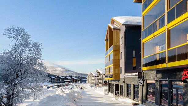 A snow-covered street with buildings, including a restaurant with a neon sign. - Levin kunkku b5 by Interhome (Kittilä)