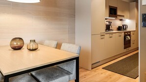 A modern kitchen with a dining area, featuring a wooden table, two chairs, and a pendant light. - Levin kunkku b5 by Interhome (Kittilä)