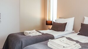 A hotel room with two beds, a window with blinds, a bedside lamp, and folded towels on the beds. - Levin kunkku b5 by Interhome (Kittilä)