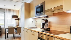 A modern kitchen with a microwave, coffee maker, and oven. There is a dining area with chairs and a table. - Levin kunkku b5 by Interhome (Kittilä)