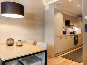 A modern kitchen with a dining area, featuring a wooden table, chairs, and a pendant light.