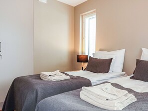 A hotel room with two beds, a window with blinds, a bedside lamp, and folded towels on the beds. - Levin kunkku b5 by Interhome (Kittilä)