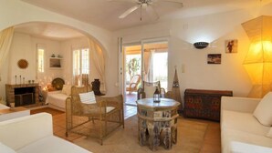 A cozy living room with white sofas, a wicker chair, a round coffee table, and a ceiling fan. - Flamenco by Interhome (Calpe/Calp)