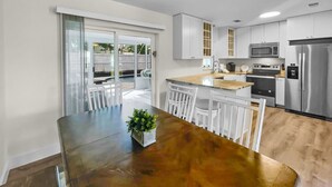 A modern kitchen with white cabinets, stainless steel appliances, and a wooden dining table with chairs.