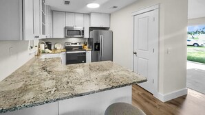 A modern kitchen with white cabinets, stainless steel appliances, and a granite countertop.