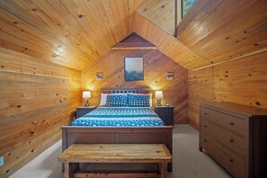 Ein gemütliches Schlafzimmer einer Holzhütte mit Bett, Nachttischlampen, einer Holzbank und einem Schminktisch.