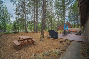 Eine Holzterrasse mit Picknicktischen und -stühlen, umgeben von einem Wald.