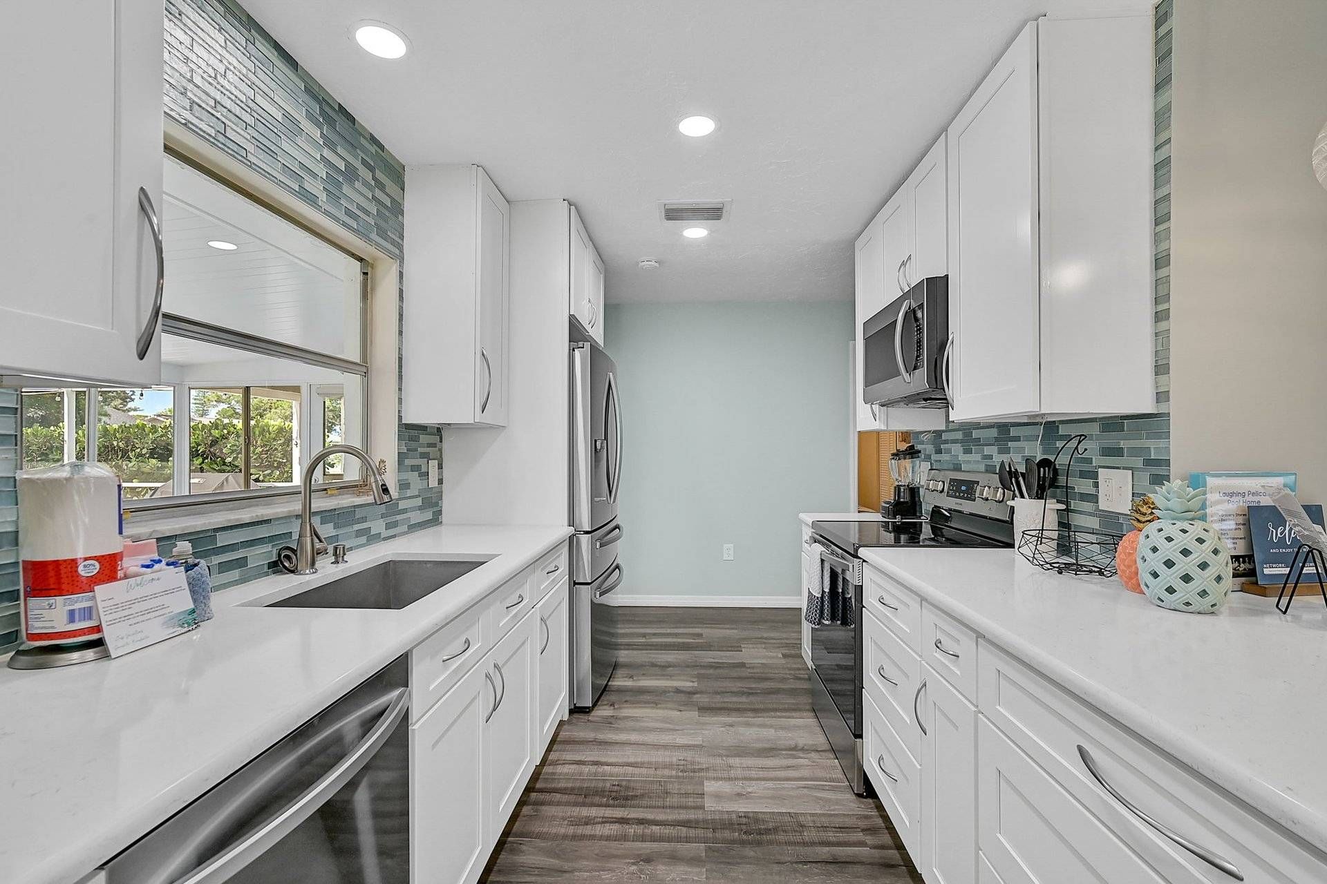 A modern kitchen with white cabinets, a stainless steel refrigerator, and a microwave.
