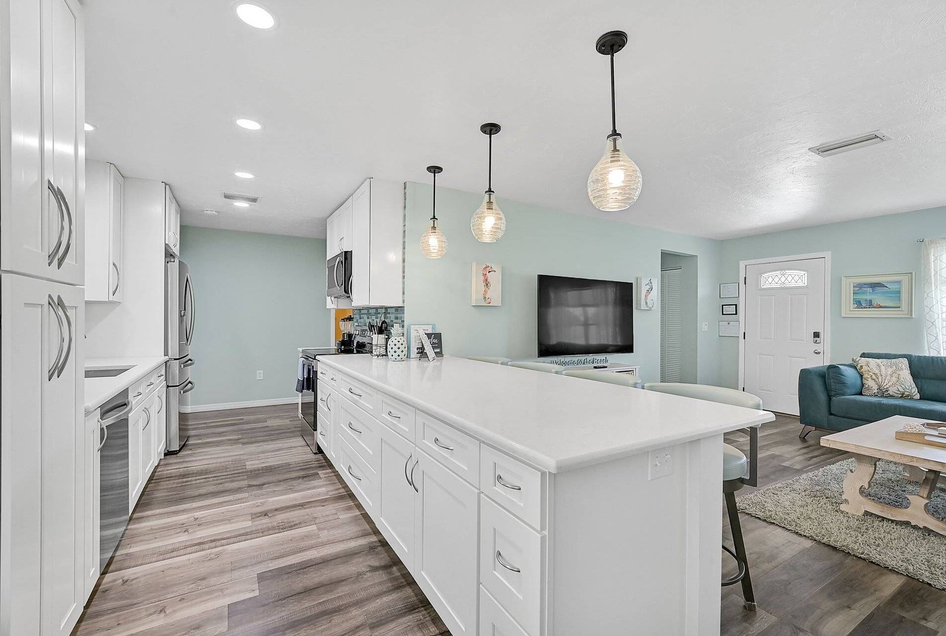 A modern kitchen with white cabinetry, a central island, and pendant lighting.