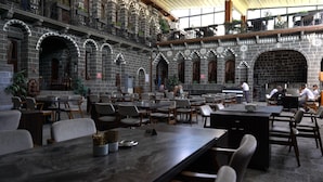 Un amplio comedor interior con paredes de piedra y varias mesas y sillas.