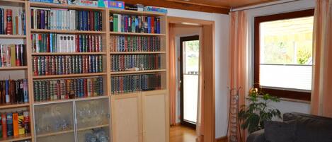 A room with a bookshelf, a sofa, and a window.